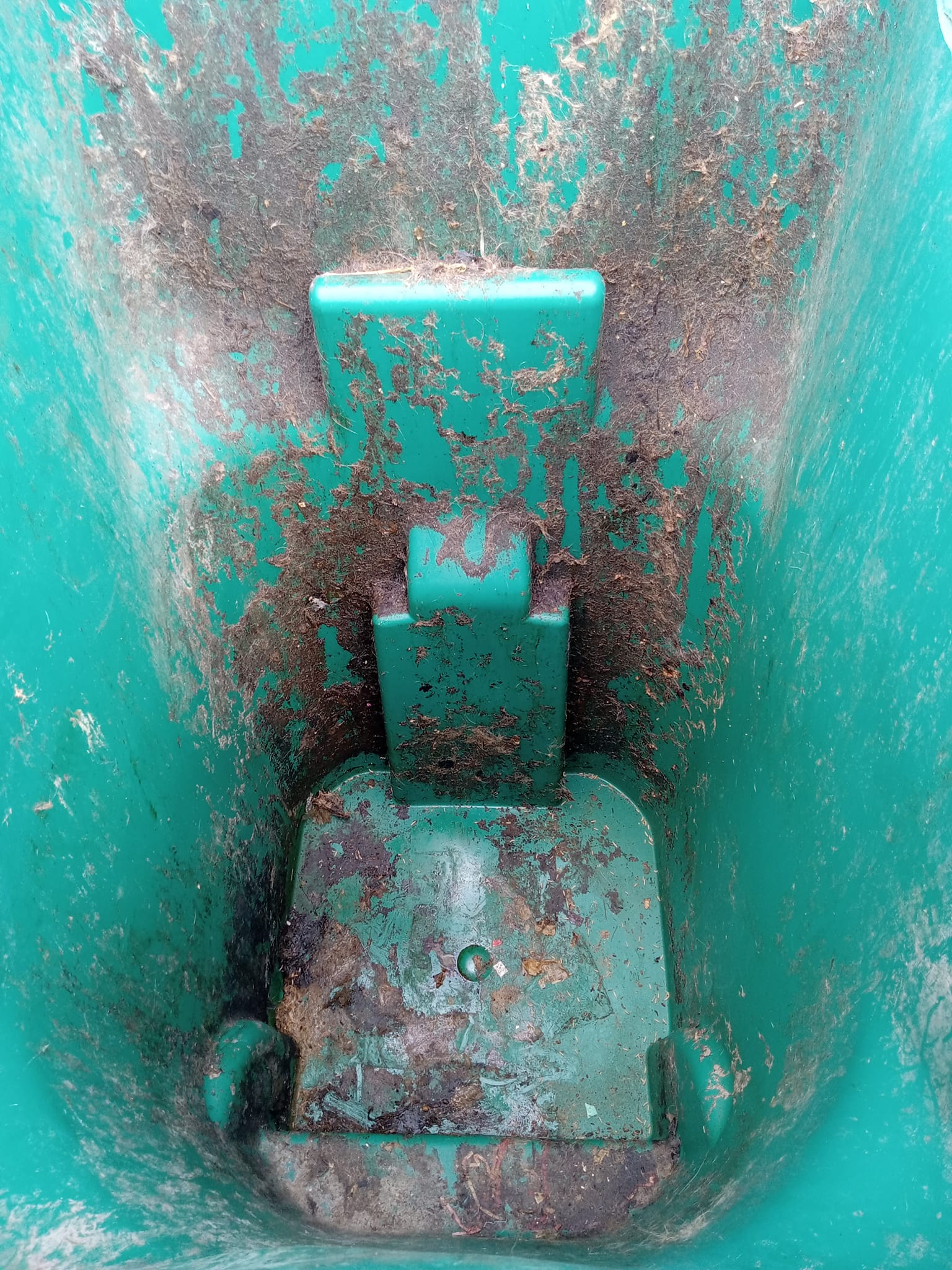 Dirty green trash can interior with grime and debris.