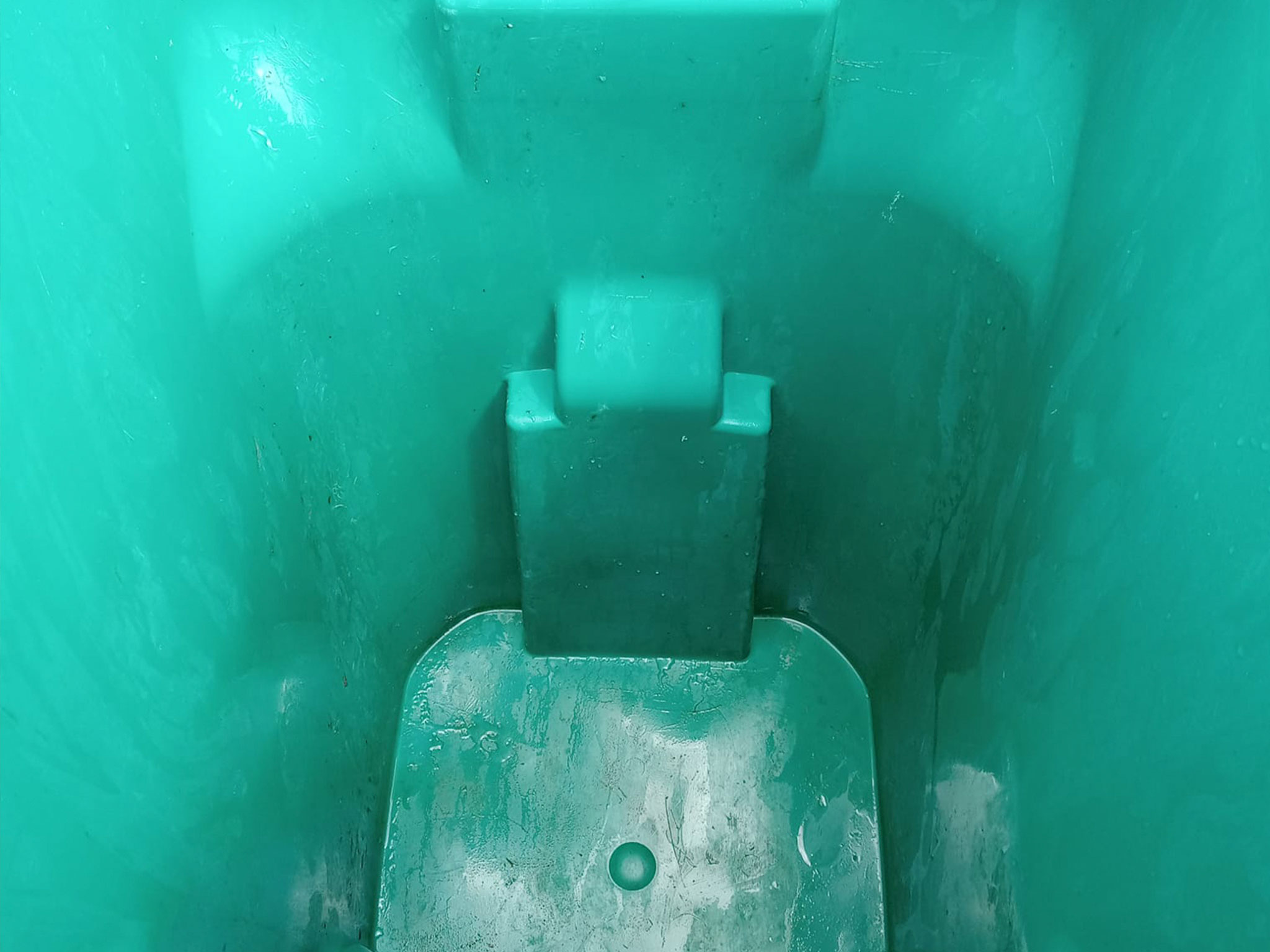 Inside of a green trash can with a lid mechanism.