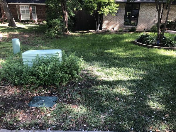 Lawn in front of house with utility boxes and trees.