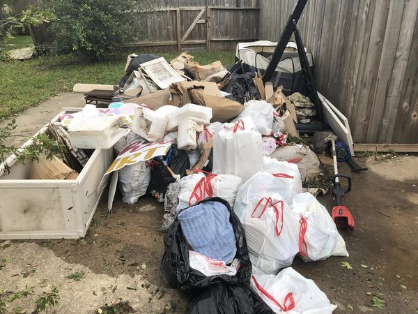 Yard waste and debris piled near a fence.