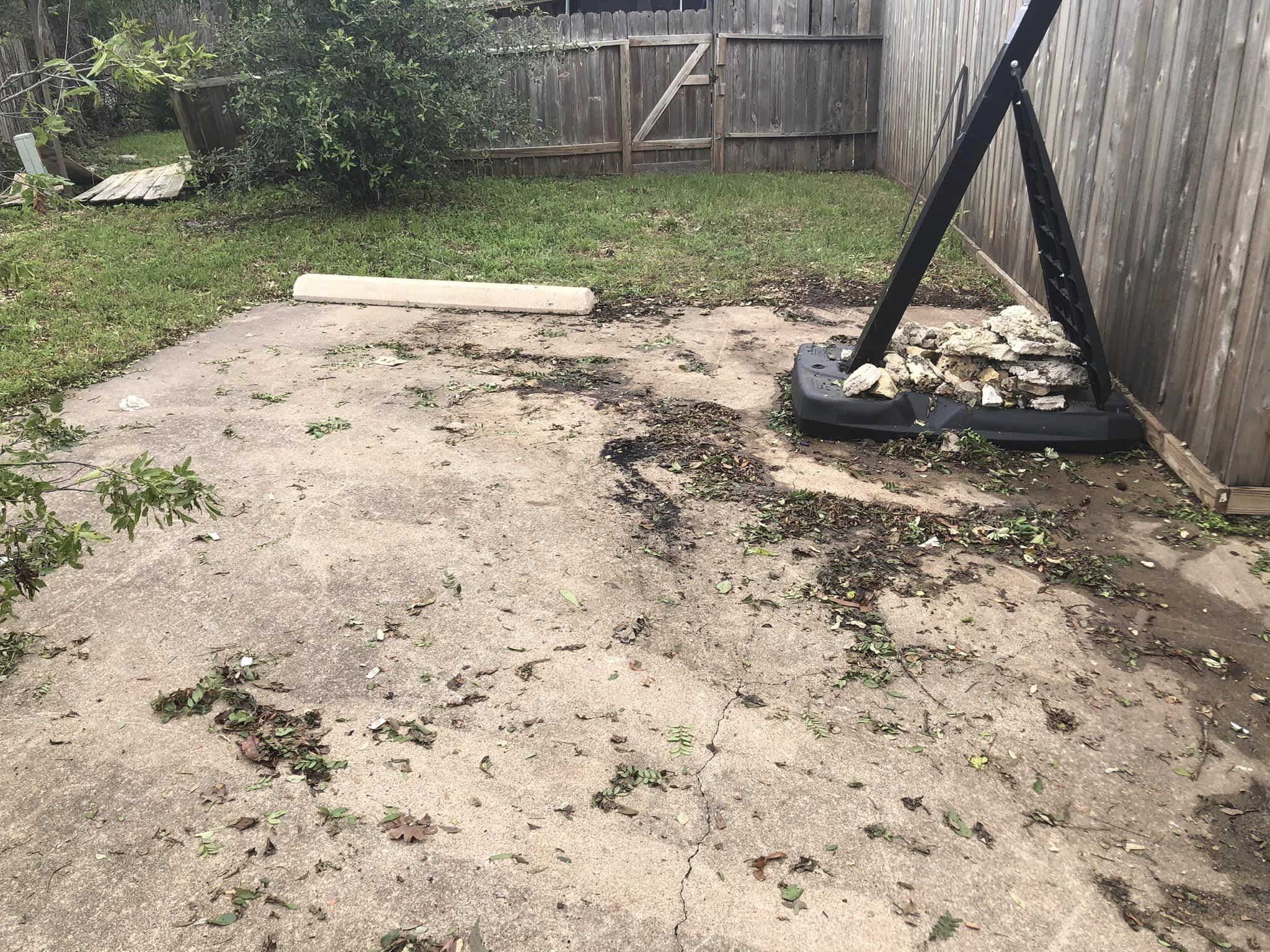 Concrete patio debris with basketball hoop and fence in background.